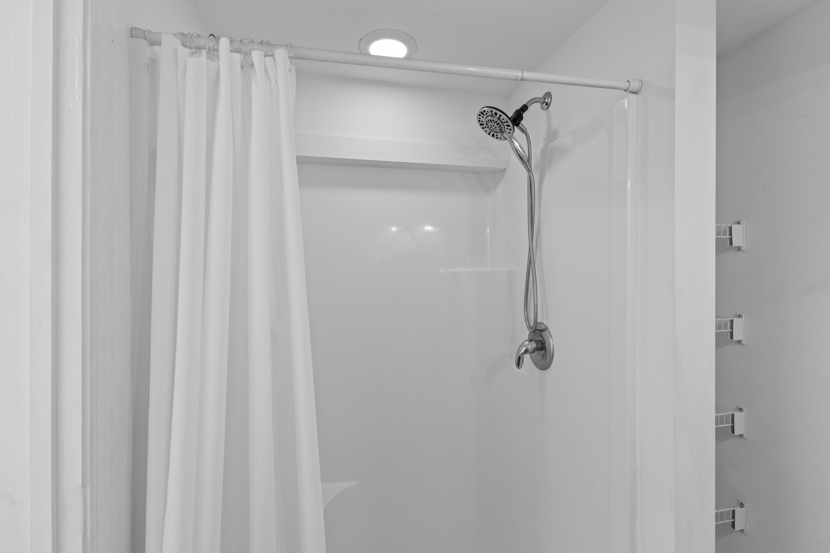 Step into your private shower sanctuary with rainfall showerhead and crisp white curtain for ultimate relaxation.
