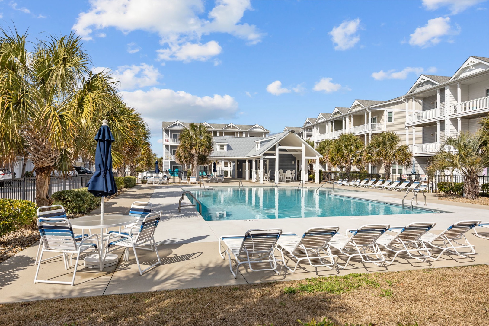 A pristine resort community with sparkling pool, tropical palms, and elegant coastal architecture under sunny blue skies.
