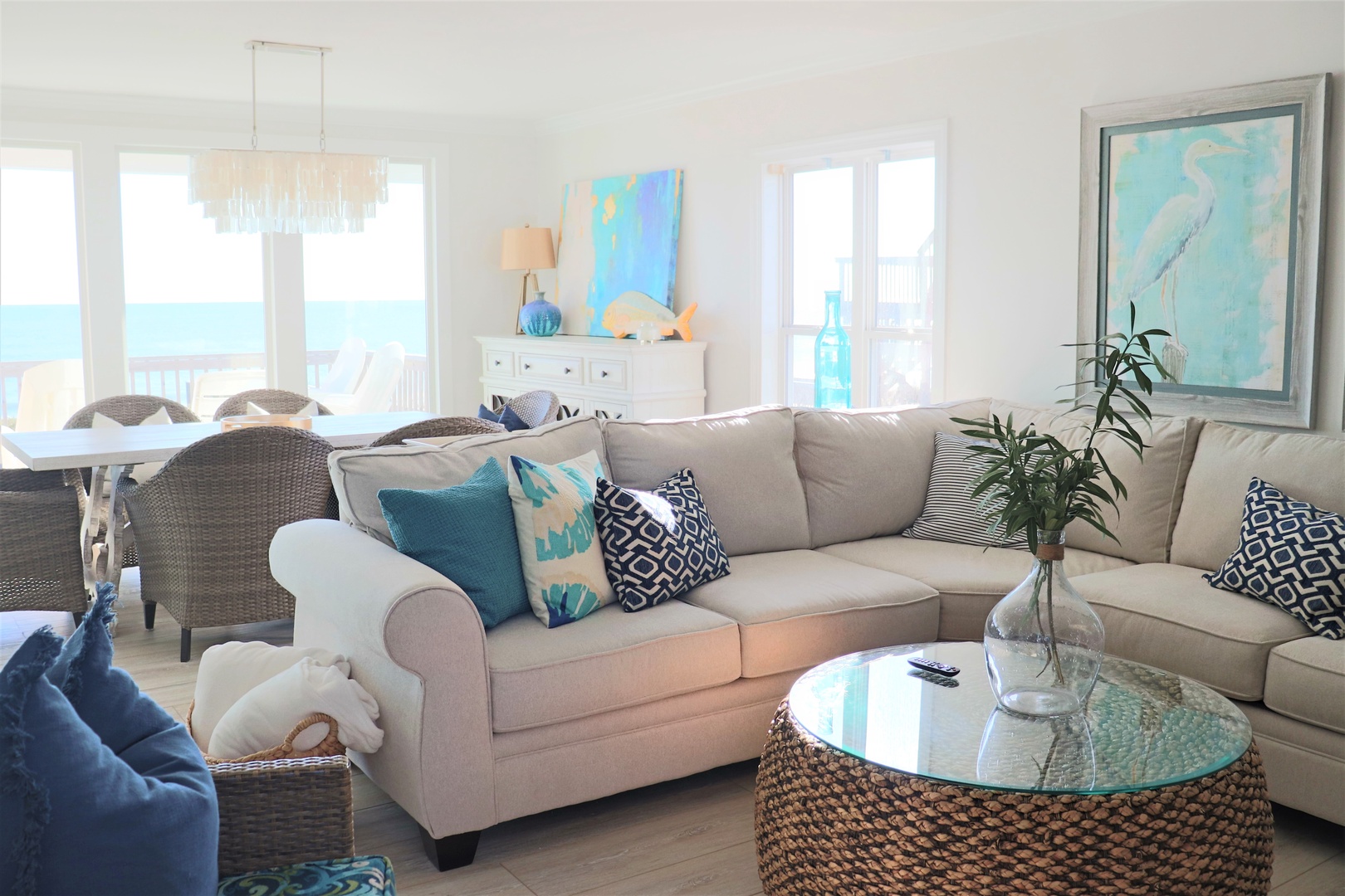 Sink into your coastal haven with ocean views streaming through floor-to-ceiling windows, where turquoise accents mirror the endless sea beyond.