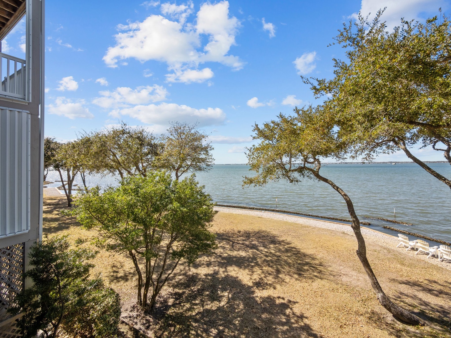Private beach access with serene waters and mature trees creating natural shade along the sandy shoreline.