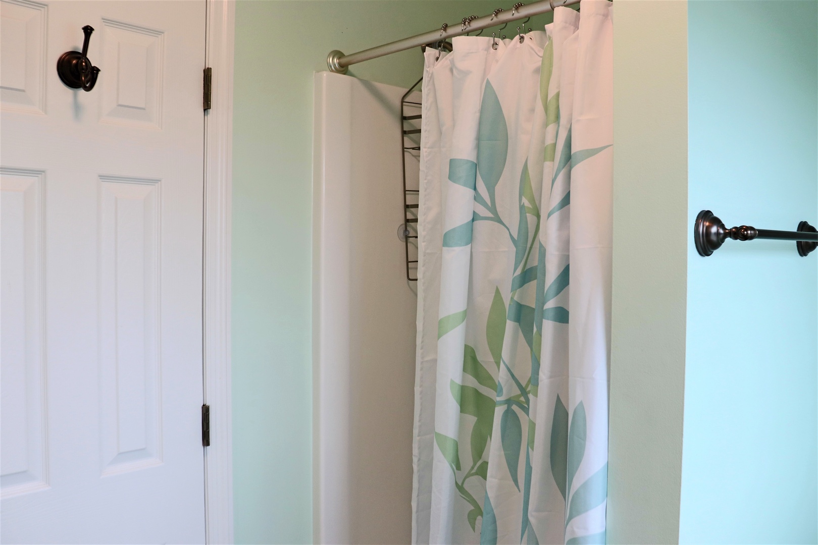 Refresh yourself in this beautifully appointed bathroom featuring a modern shower with stylish botanical curtains and soothing mint walls.