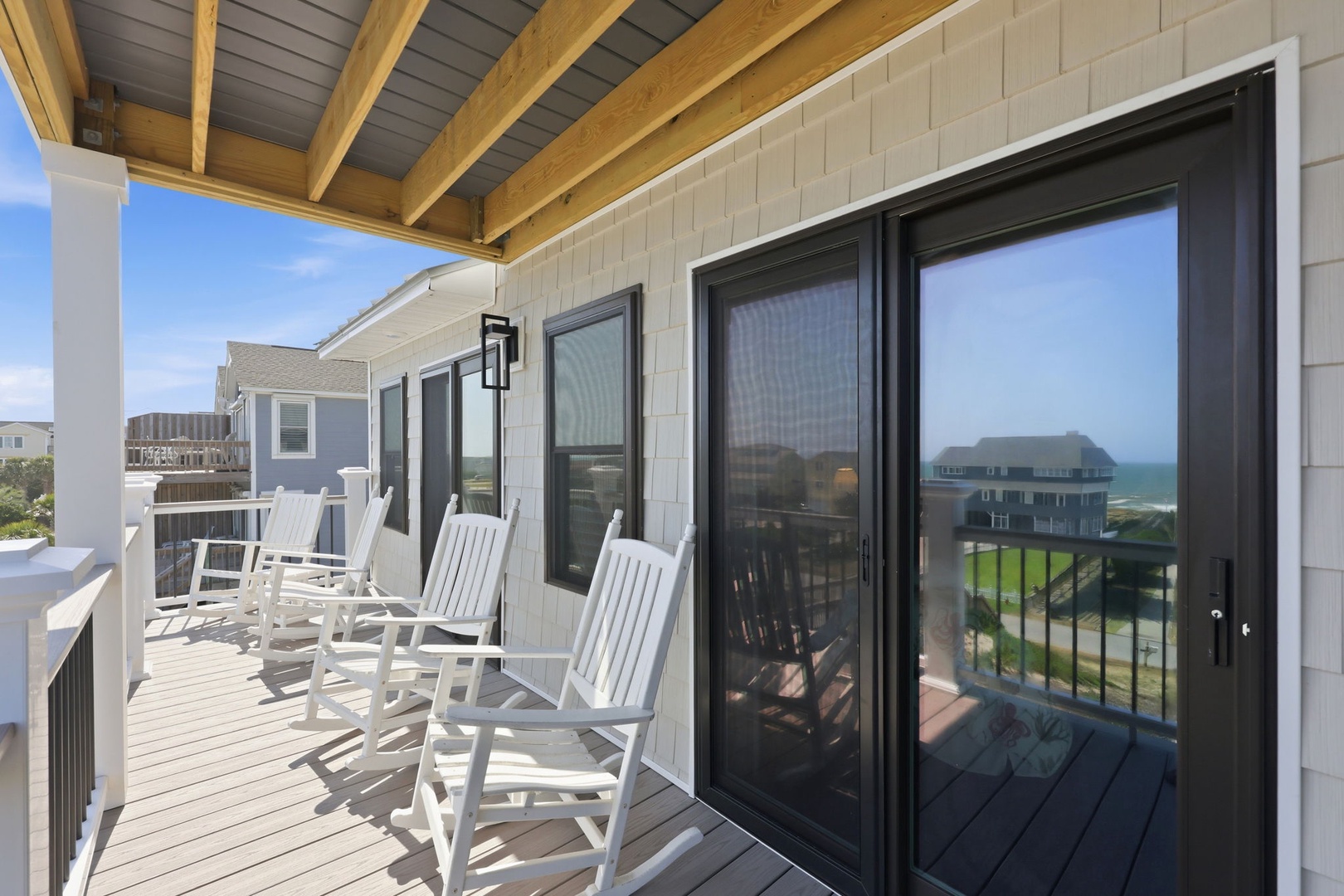 Settle into a rocking chair on your private balcony and soak in stunning coastal views stretching to the horizon. The ocean breeze, wood-beam ceiling, and serene setting create your perfect beach escape.