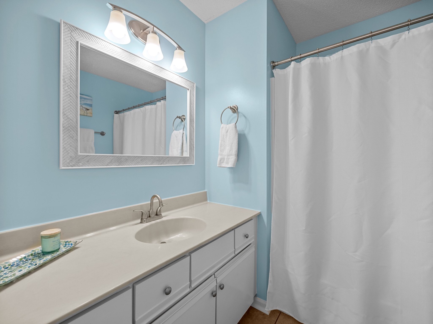 Refresh in your private bathroom with calming blue walls, fresh towels, and modern lighting creating a spa-like retreat.