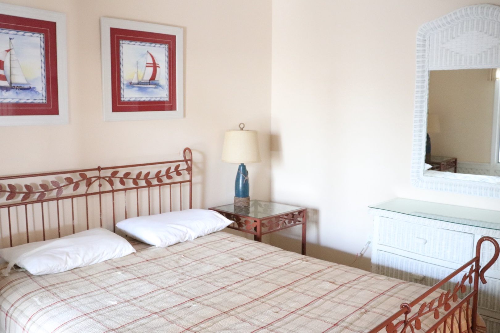 Drift off to nautical dreams in this coastal-themed bedroom with red metal beds and charming sailboat artwork.