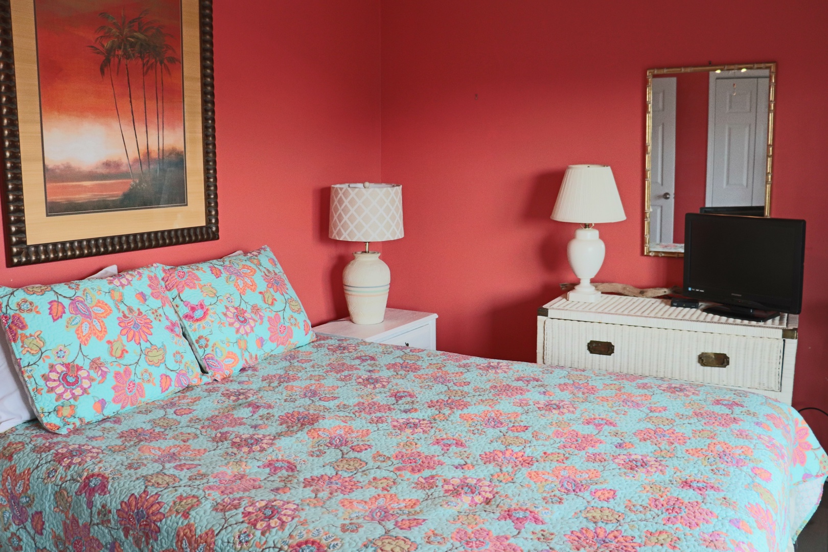 Drift off in your tropical-themed bedroom featuring vibrant coral walls, cheerful floral bedding, and coastal artwork that creates a warm, welcoming retreat.