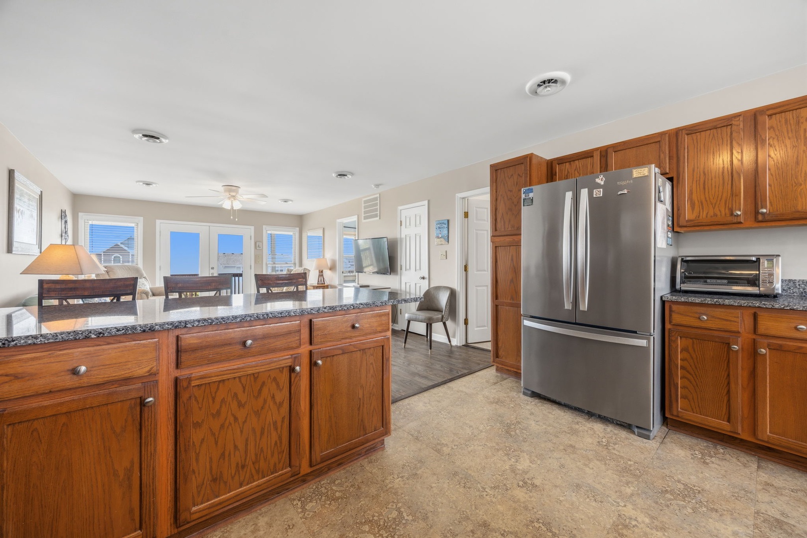 Your spacious kitchen features granite countertops, stainless steel appliances, and warm wood cabinetry with ocean views through oversized windows.