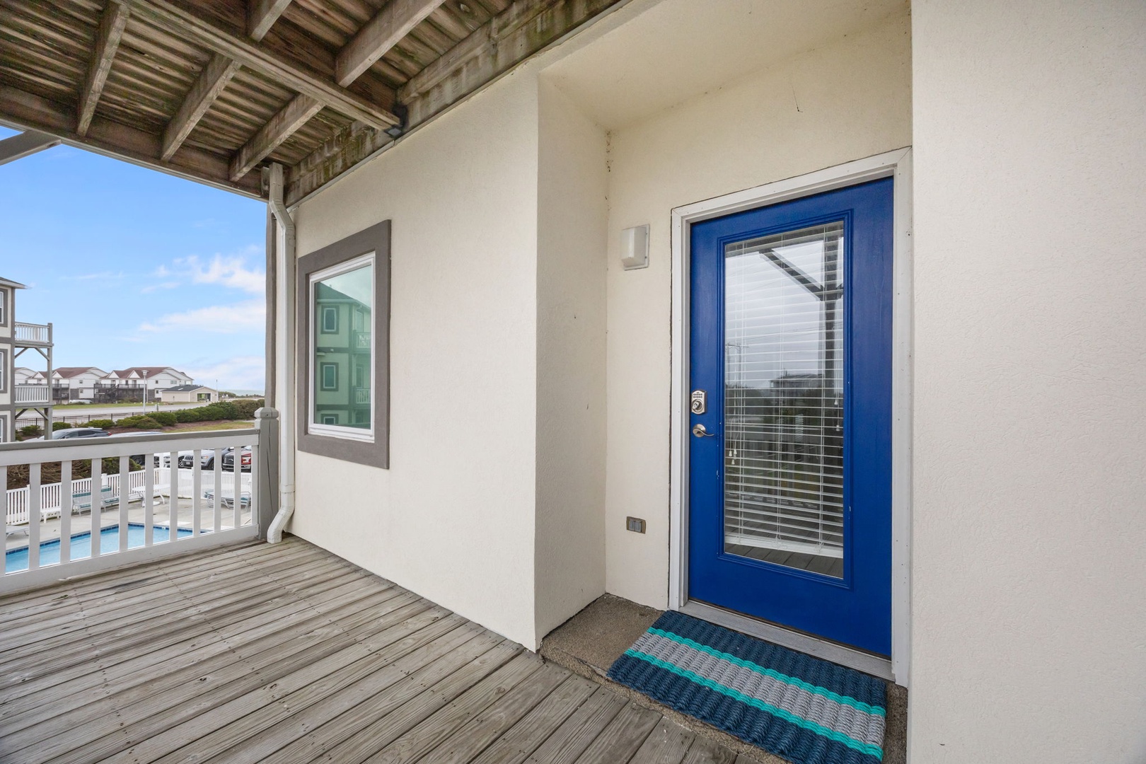 Welcoming beach house entrance with vibrant blue door and coastal neighborhood views from your private covered porch.