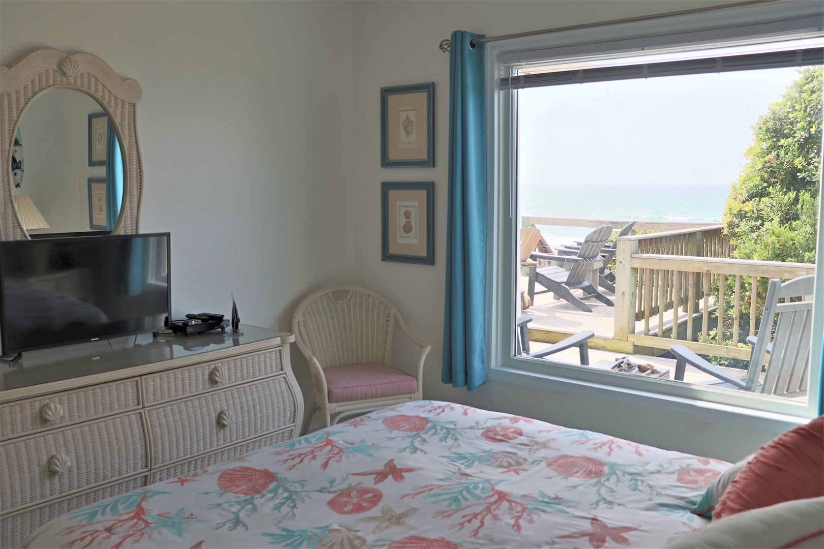 Your bedroom blends coastal charm with stunning views, featuring wicker furnishings, vibrant bedding, and a private deck overlooking the sea.