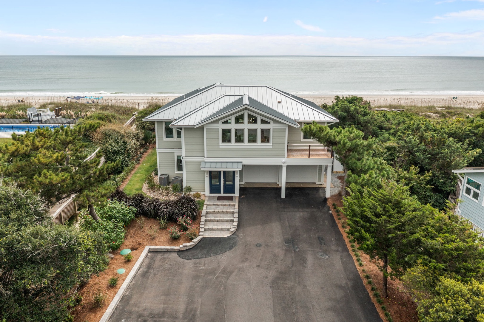 Coastal retreat with beachfront access and ocean views, featuring modern architecture surrounded by lush landscaping.