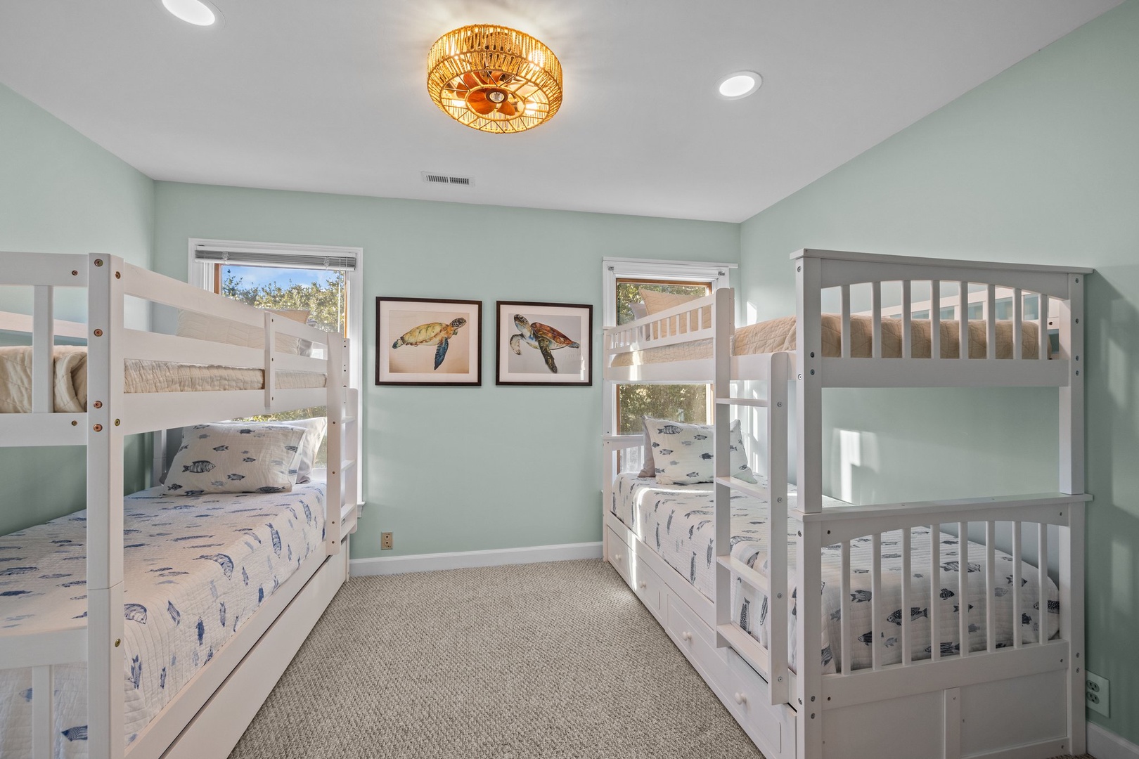 Your kids will love this charming bunk room with two sets of beds, ocean-themed linens, and a warm coastal chandelier overhead.