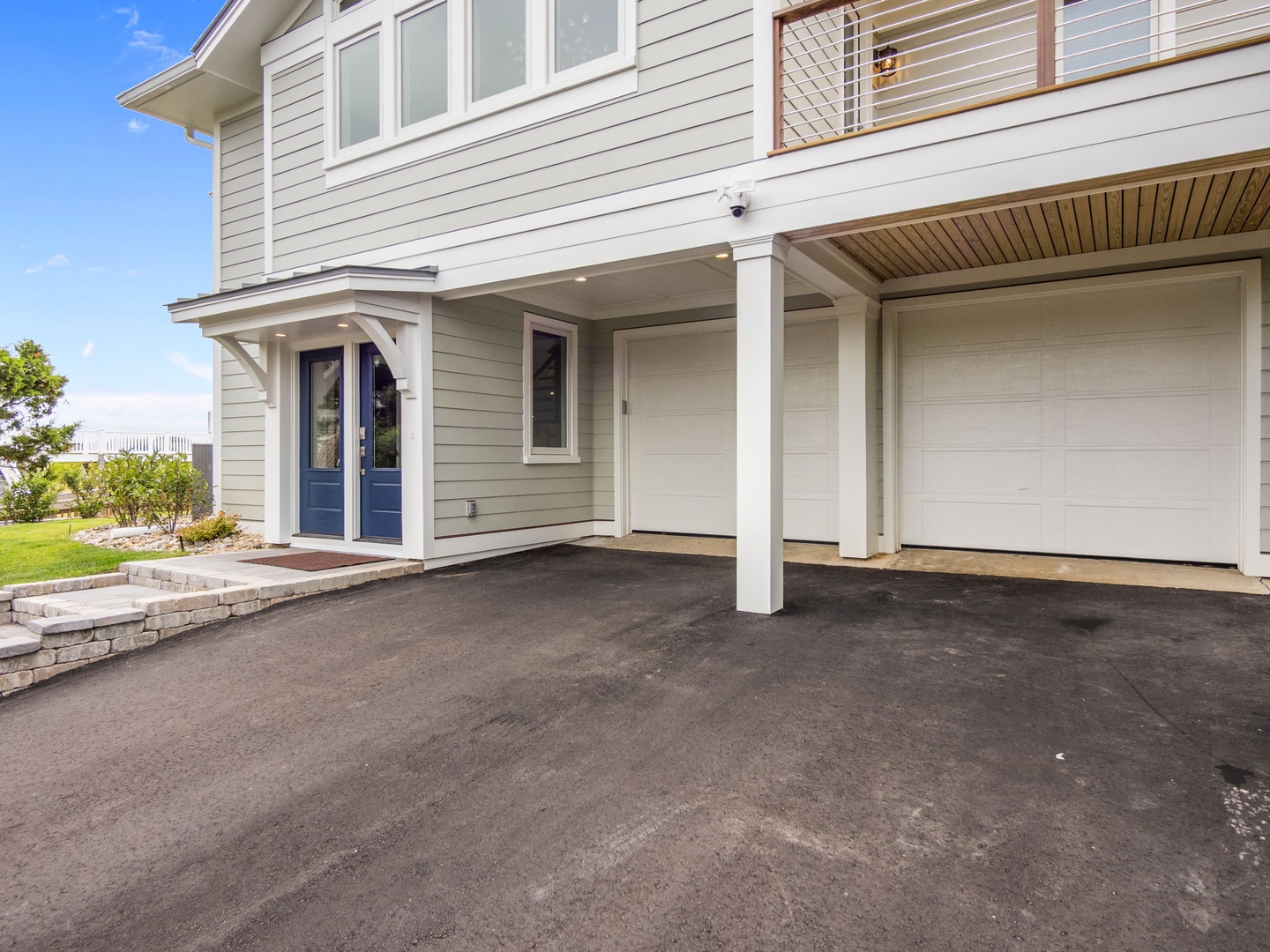 Modern coastal home with covered parking and welcoming blue front entrance surrounded by landscaped gardens.
