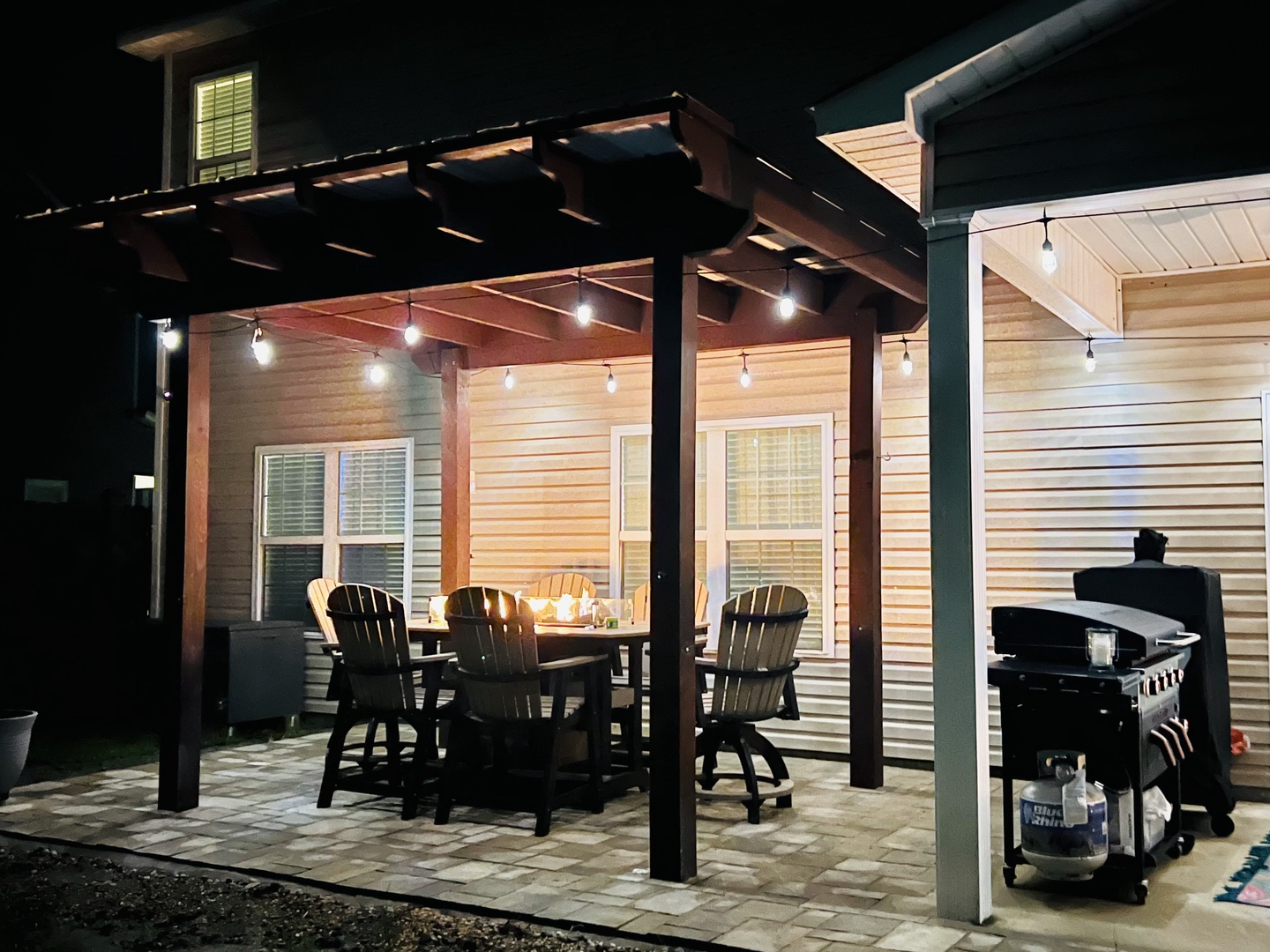 Your private patio glows warmly under string lights, perfect for evening meals and grilling adventures together.