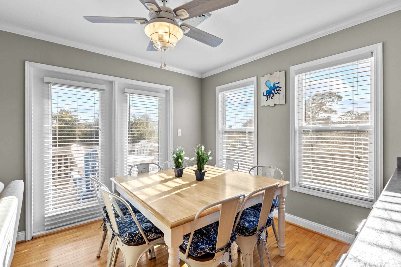 Gather around your bright dining table where natural light streams through four windows, creating the perfect spot for meals and conversation.