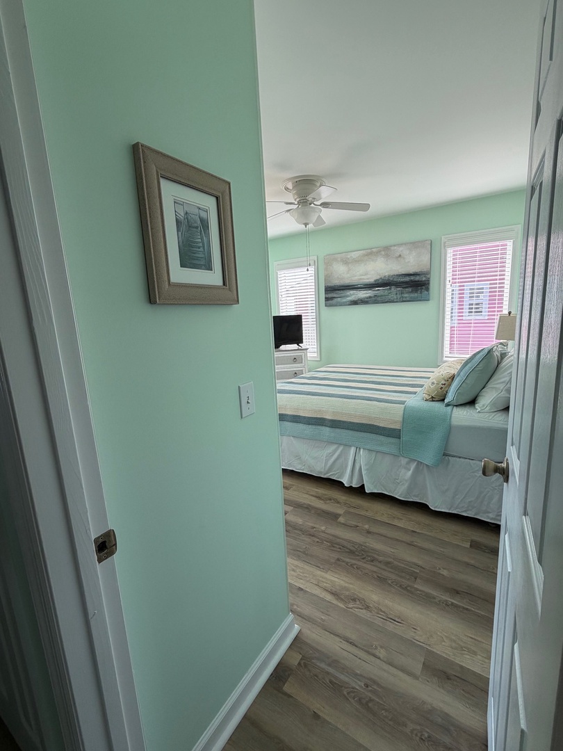 Your peaceful seafoam-green bedroom features a cozy bed and warm wood floors, creating a calming coastal retreat for restful nights.