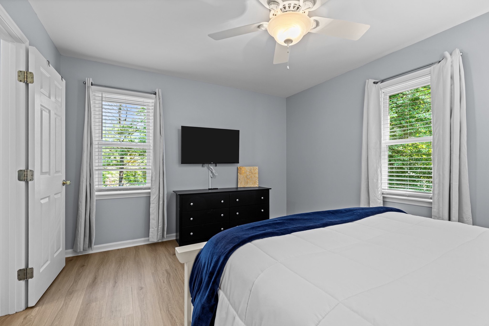 Rest easy in your peaceful bedroom with crisp linens, entertainment, and leafy garden views through bright windows.