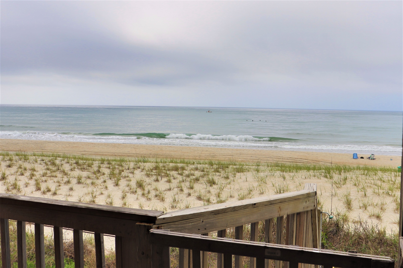 Ocean waves and sandy shores stretch endlessly before this beachfront property, with wooden deck access leading to pristine coastal beauty.