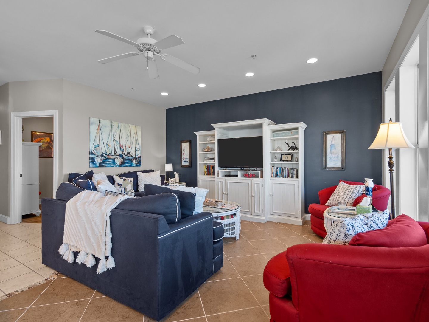 Relax in your bright living room with comfy navy sectional, vibrant red chairs, and entertainment center.