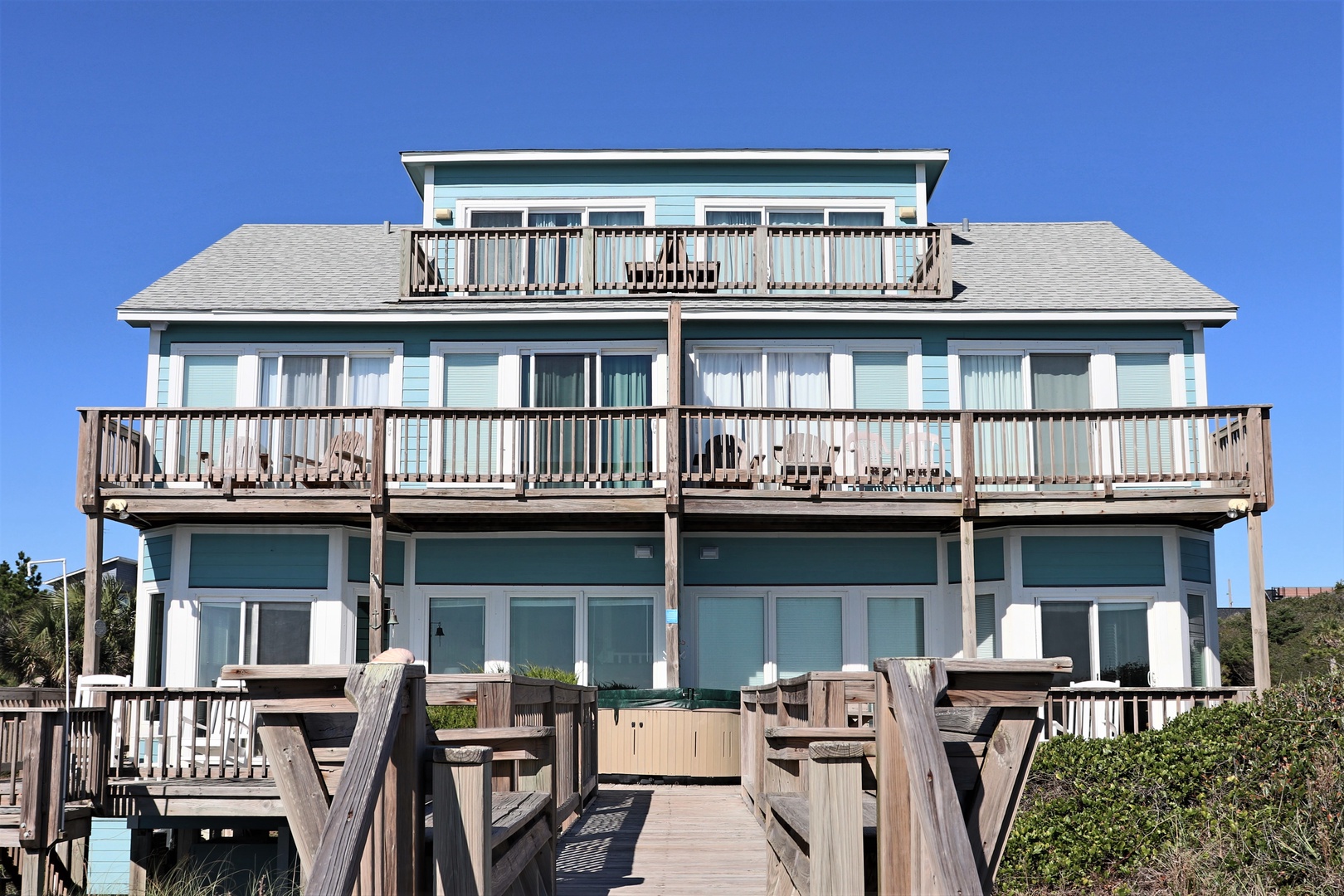 Charming beachfront property with multiple levels of outdoor decking and balconies overlooking the coast.