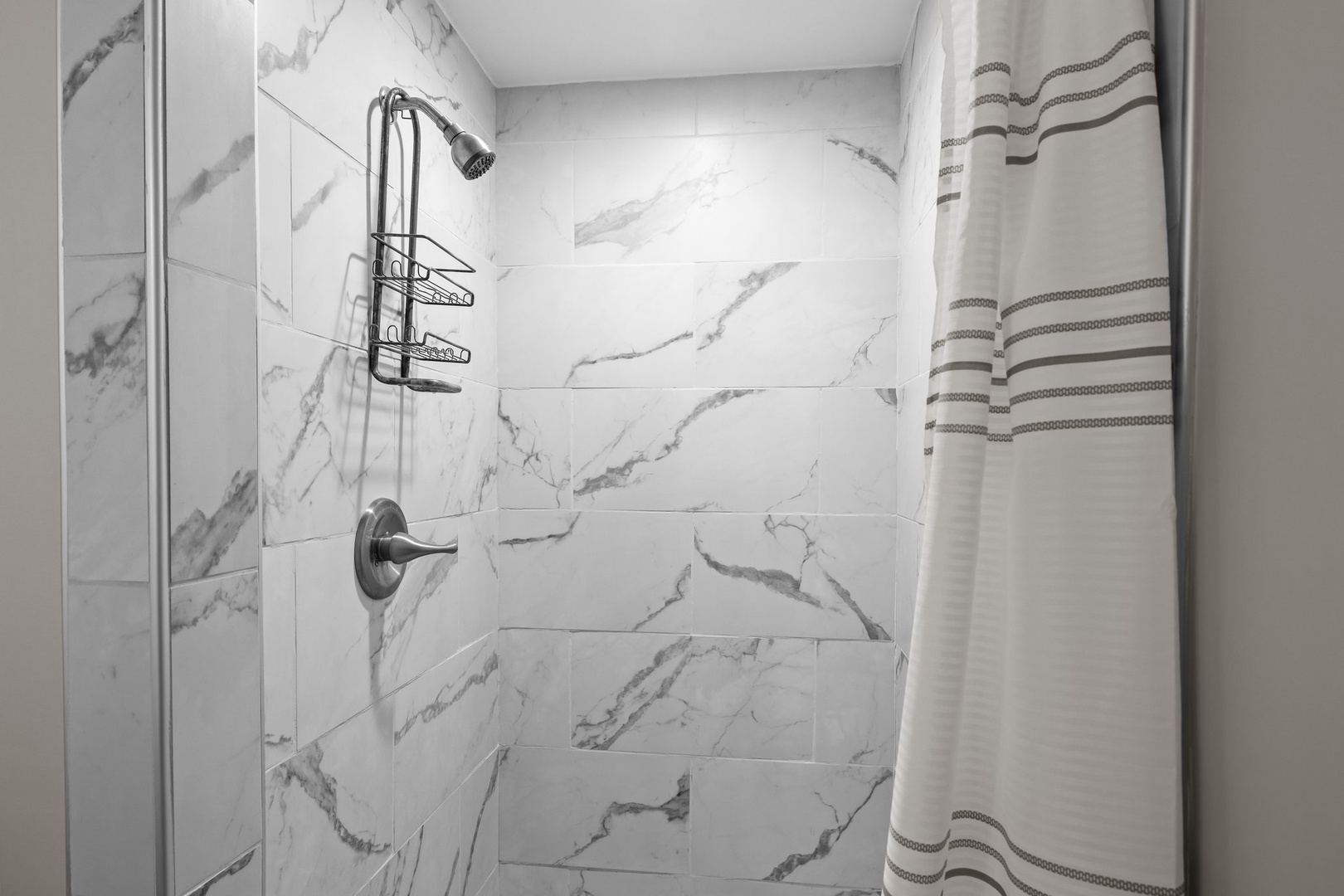Refresh in your elegant marble-look shower with thoughtful organizers and fresh linens waiting for you.