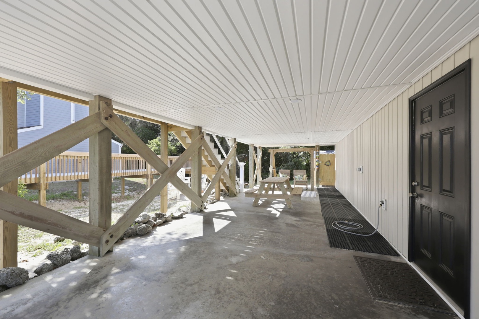 Covered ground-level parking and entry area with sturdy wooden support beams and ample space for vehicles and outdoor gear.