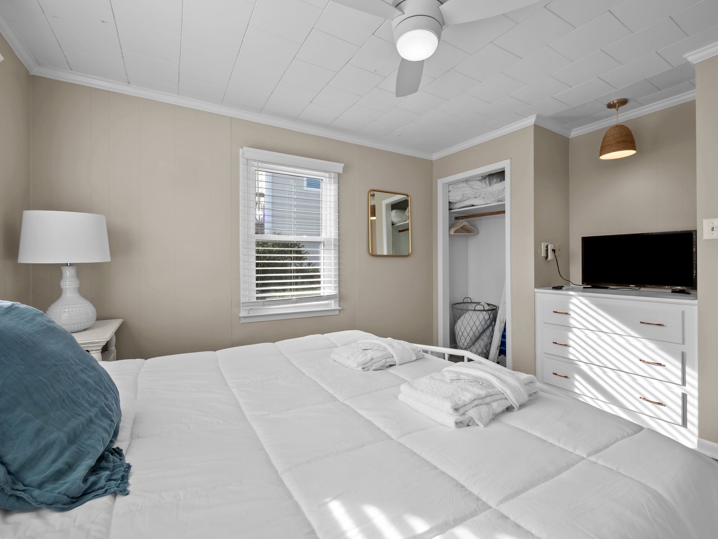 Drift off in this serene bedroom where soft morning light filters through blinds, creating peaceful shadows across crisp linens and thoughtful touches.