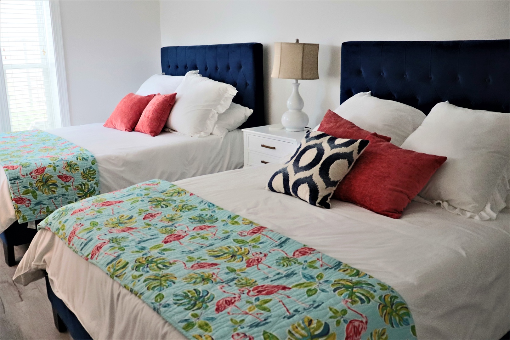 Sink into these plush beds with navy tufted headboards and vibrant tropical touches for your perfect twin getaway.