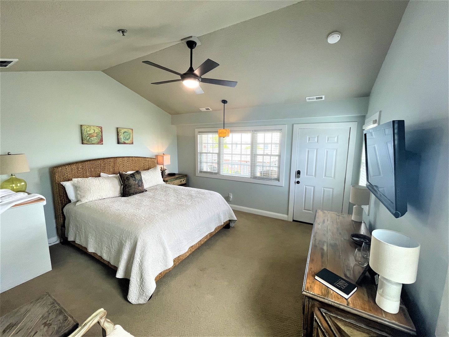 Relax in your serene bedroom with wicker headboard, plush linens, and gentle ceiling fan. Natural light streams through large windows.