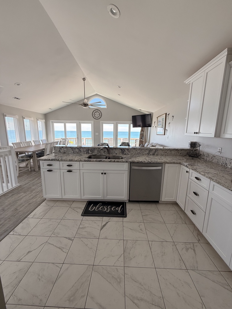 Bright, modern kitchen bathed in natural light, featuring elegant marble-look tile backsplash, exposed beam character, and ample storage for your culinary adventures.