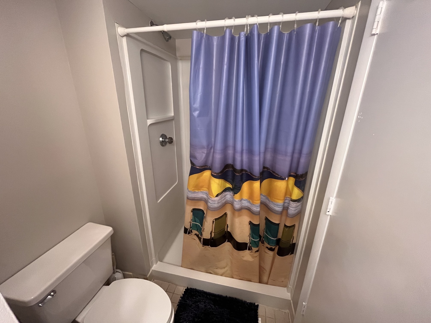 Your private bathroom features a refreshing shower with colorful curtain, creating a cheerful space to start your day.
