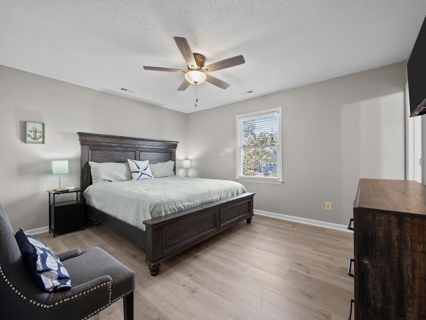 Sink into the plush king bed while your overhead fan creates a gentle breeze. Natural light streams through your window as you unwind in this serene retreat.