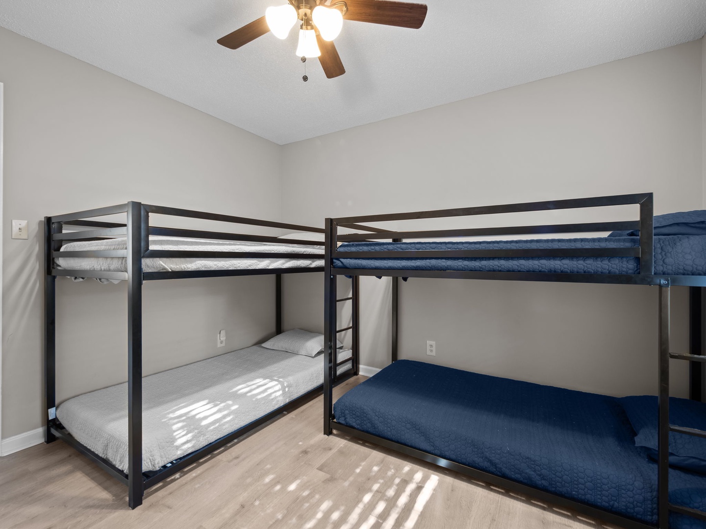 Four bunk beds with cozy blue linens await your group in this sunlit room with ceiling fan comfort.