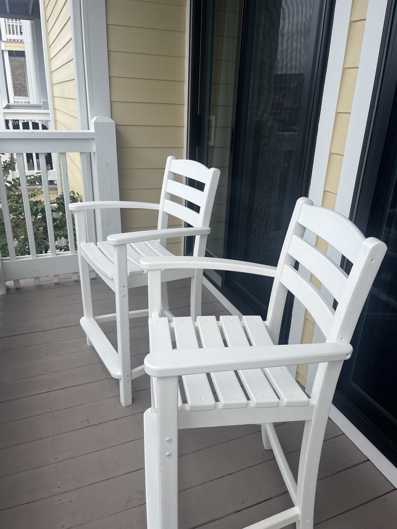 Step onto your private balcony where white wooden chairs invite you to unwind and soak in peaceful moments.
