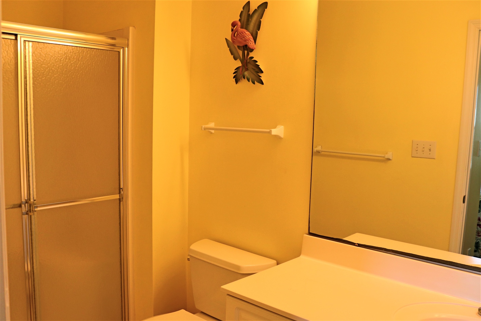 Step into your private bathroom featuring warm golden tones, a spacious walk-in shower, and thoughtful grab bars for safety and comfort.