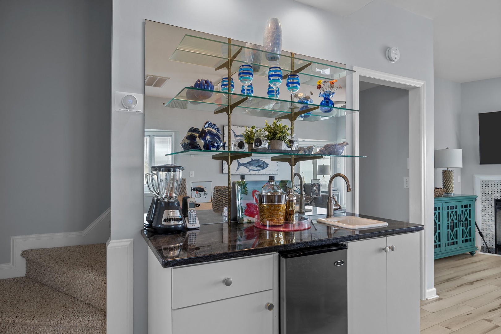 Your stylish wet bar features glass shelving, granite counters, and mini fridge—perfect for entertaining with coastal charm.