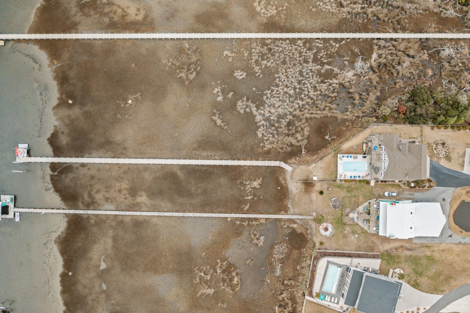 Aerial view of beachfront properties with private docks extending into calm waters, showcasing the coastal setting and waterfront access.