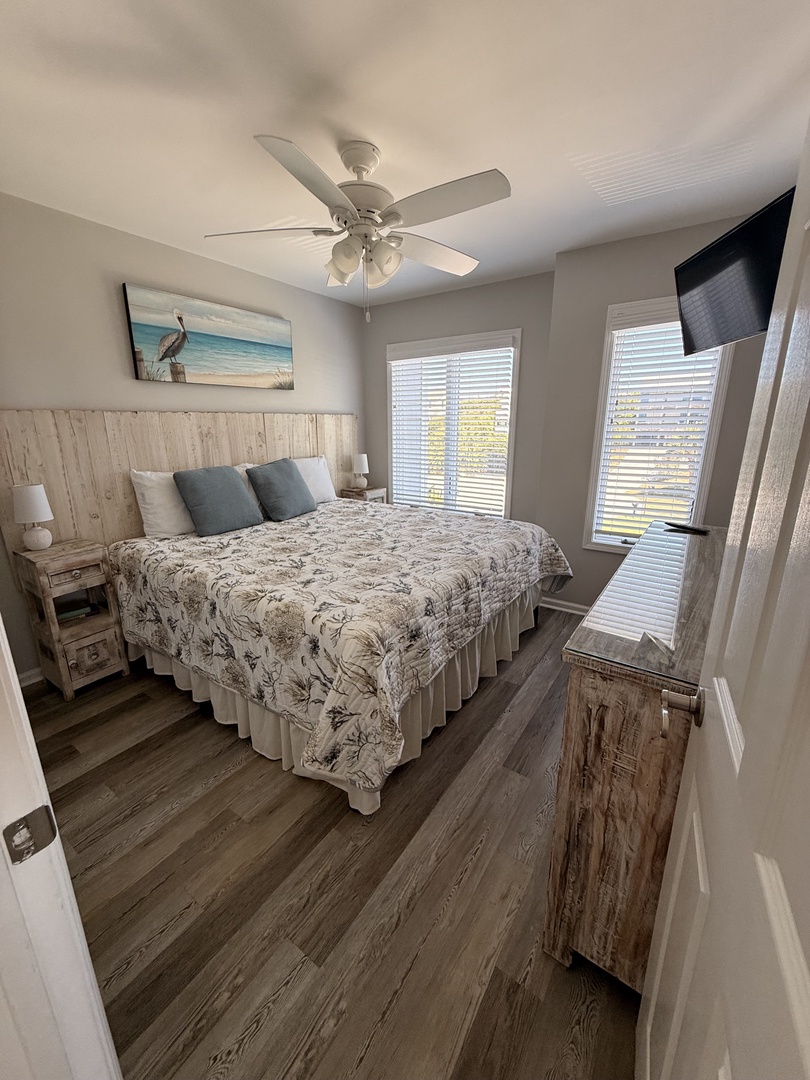 Your bright, coastal-inspired bedroom awaits with a plush bed, warm wood-toned floors, and skylight views that bring natural light into your restful sanctuary.
