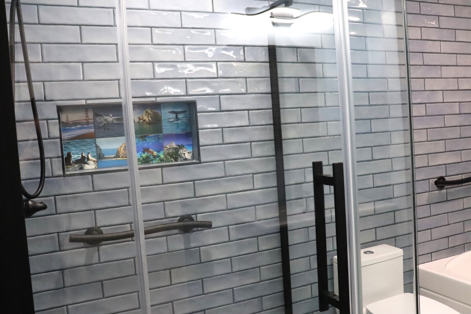 Modern bathroom with sleek subway tile and glass-enclosed shower. Thoughtful ocean-themed accents add coastal charm to your personal retreat.