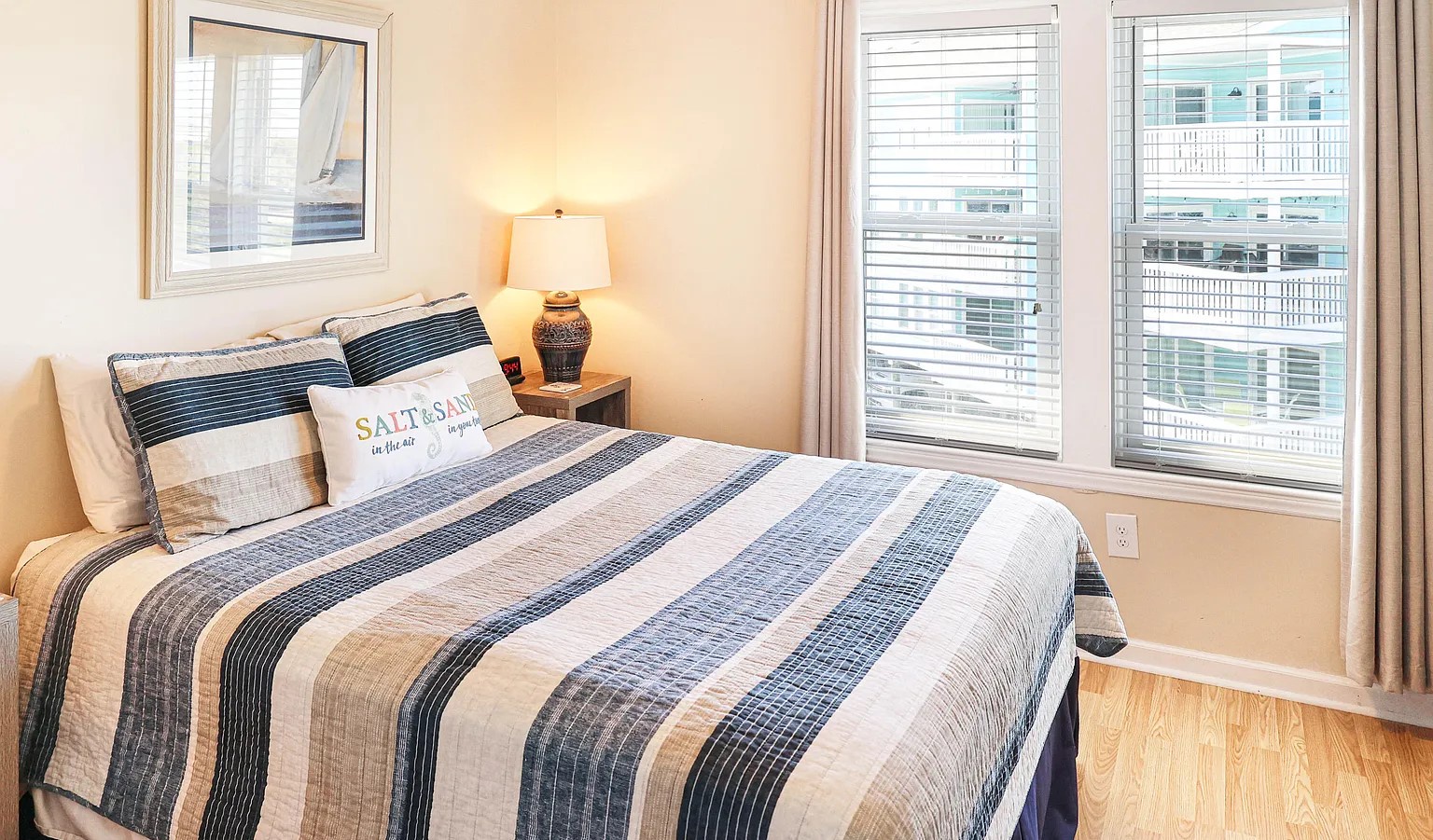 Wake up to stunning city skylines through your bedroom's expansive windows, with striped linens and warm lighting creating the perfect urban retreat.