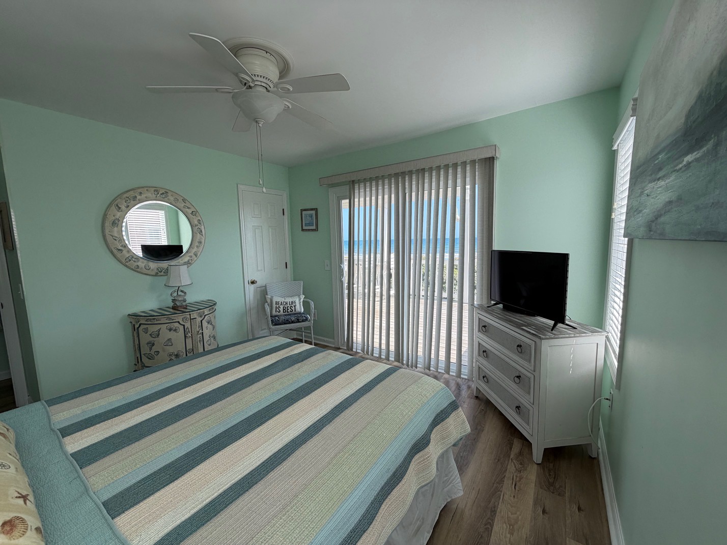 Your coastal bedroom features soothing sea-green walls, striped bedding, and ocean artwork creating your perfect seaside retreat.