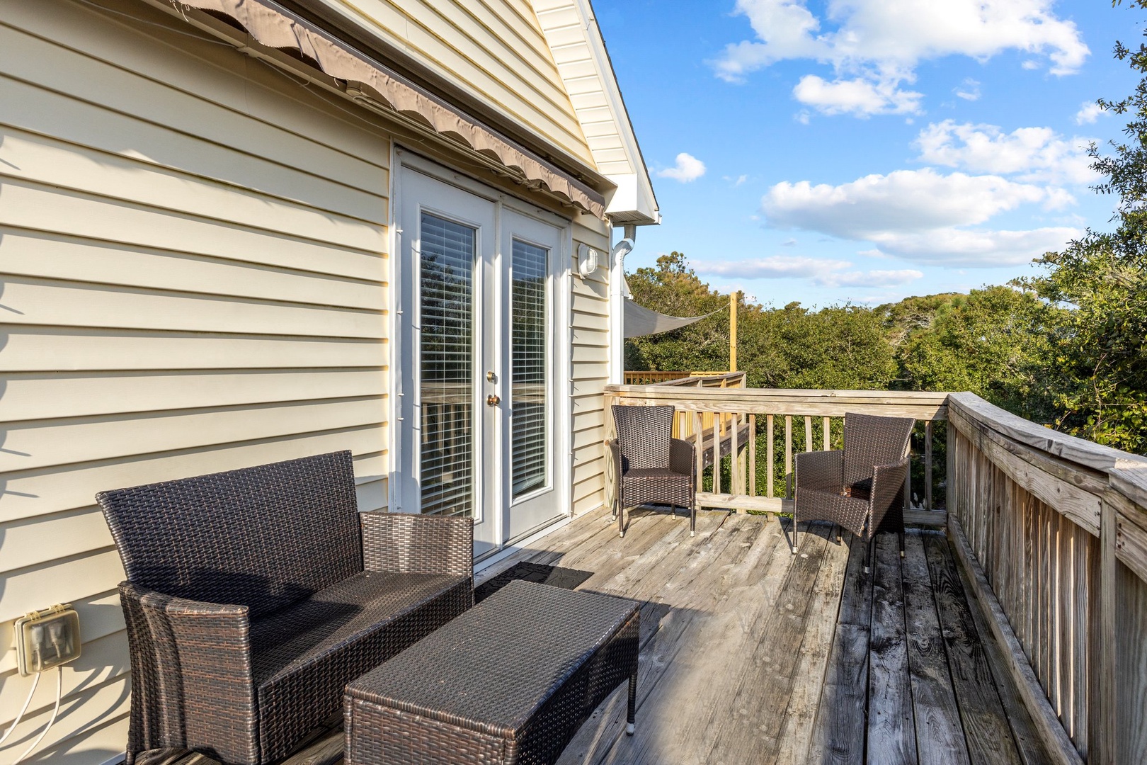 Step onto your private deck where comfortable wicker seating awaits overlooking peaceful treetops—perfect for morning coffee or evening relaxation.