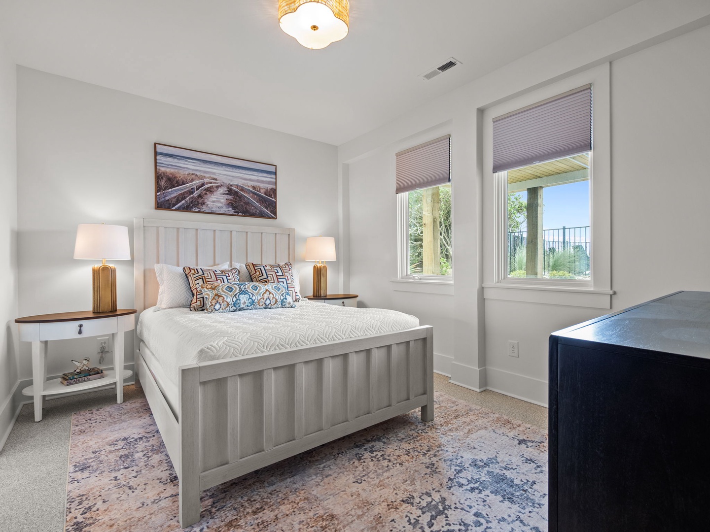 Unwind in this bright bedroom with comfortable furnishings, warm lighting, and peaceful views of the surrounding landscape through your private windows.