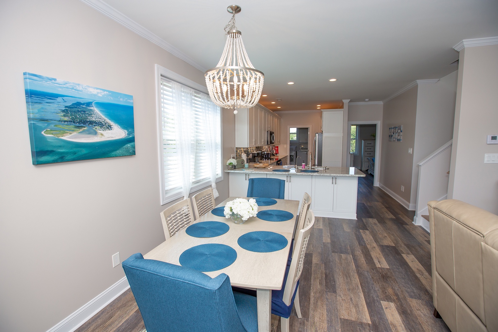 Gather around your elegant dining table beneath this stunning chandelier, where the open kitchen invites culinary adventures.