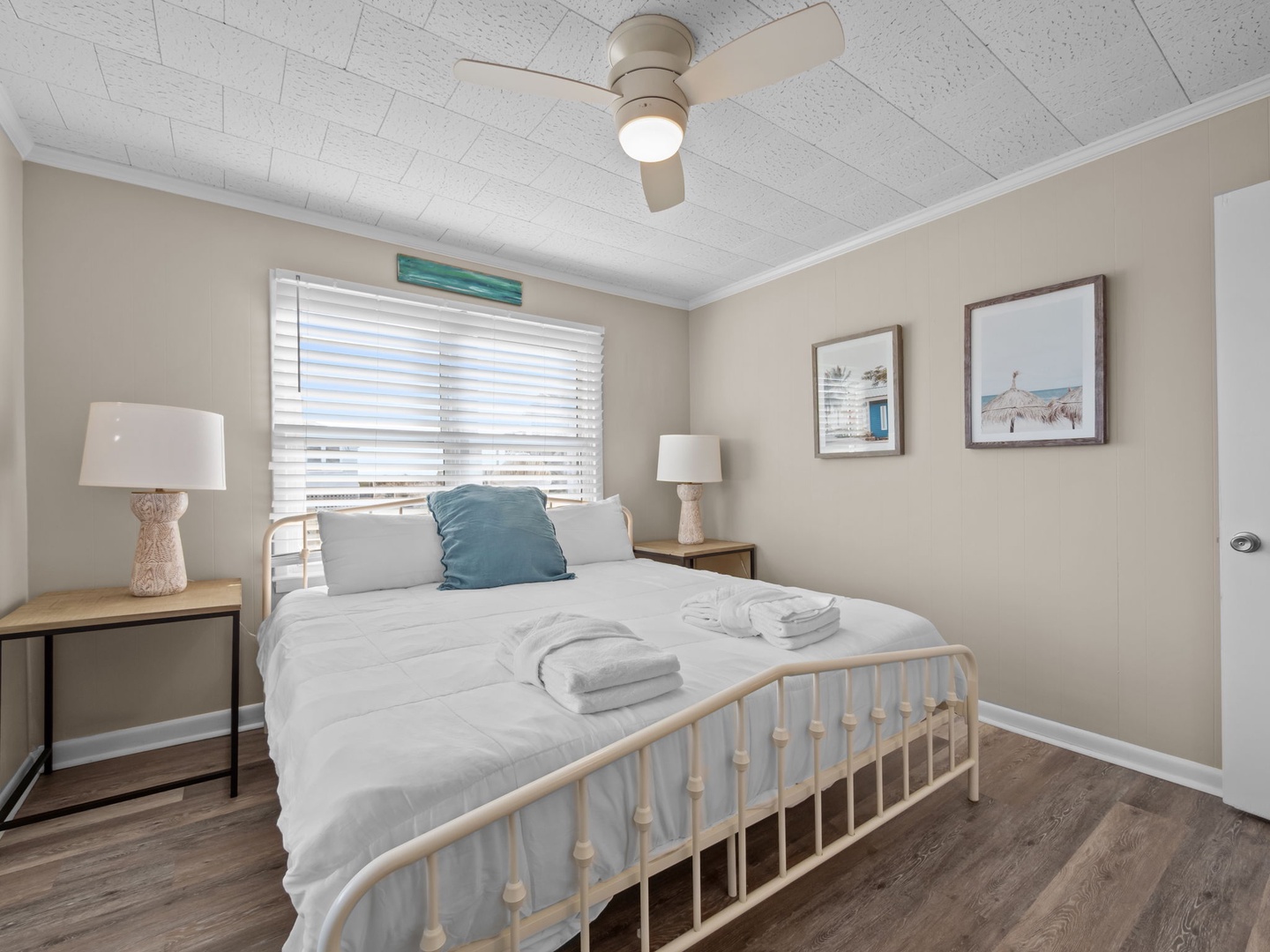Sink into crisp linens and coastal comfort in your serene bedroom, where gentle breezes from the ceiling fan help you drift into peaceful sleep.