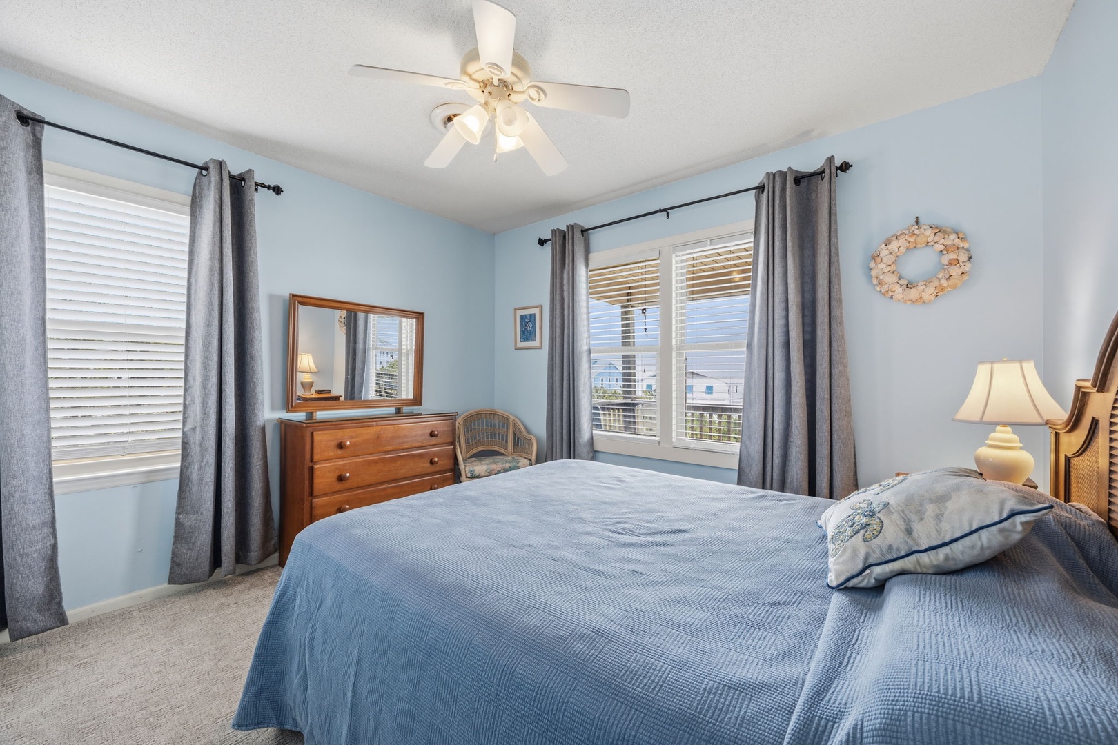 Relax in your peaceful bedroom with soft blue walls, comfortable bedding, and gentle ceiling fan keeping you cool.