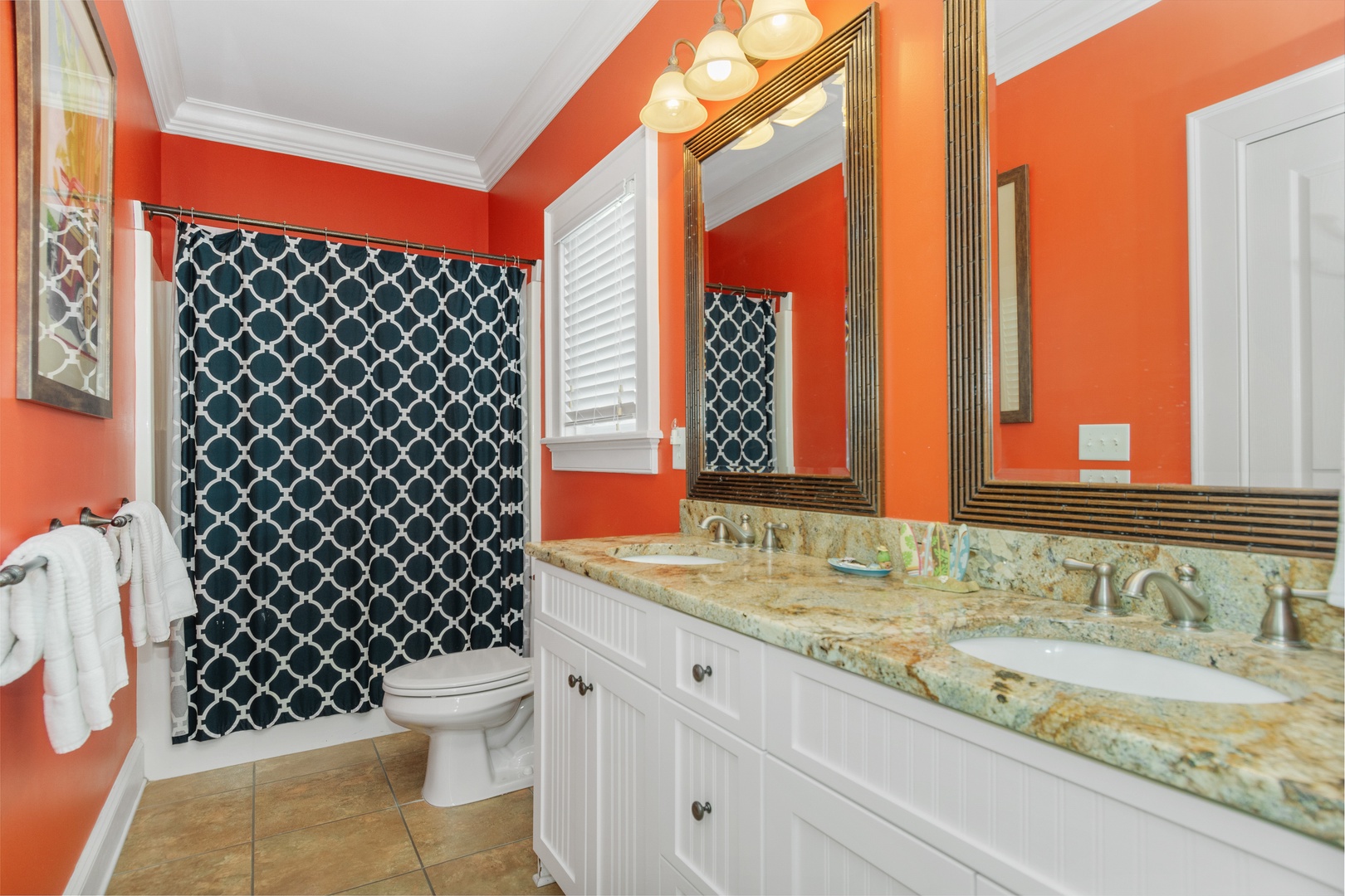Refresh in your vibrant bathroom featuring elegant granite countertops, dual vanity, and stylish geometric shower curtain.