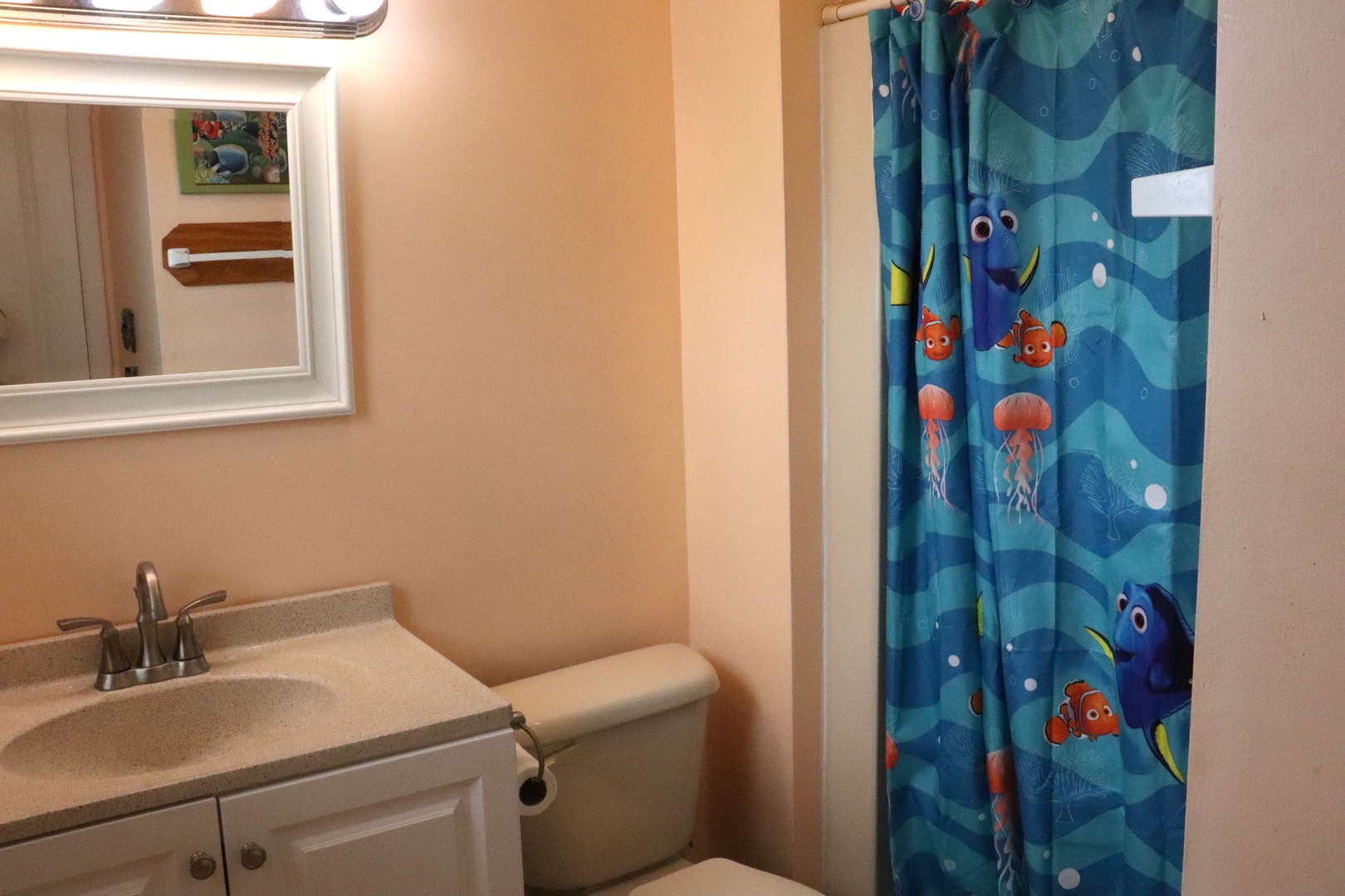 Your little ones will love the playful Finding Nemo shower curtain in this cheerful bathroom, complete with a clean vanity and bright mirror.
