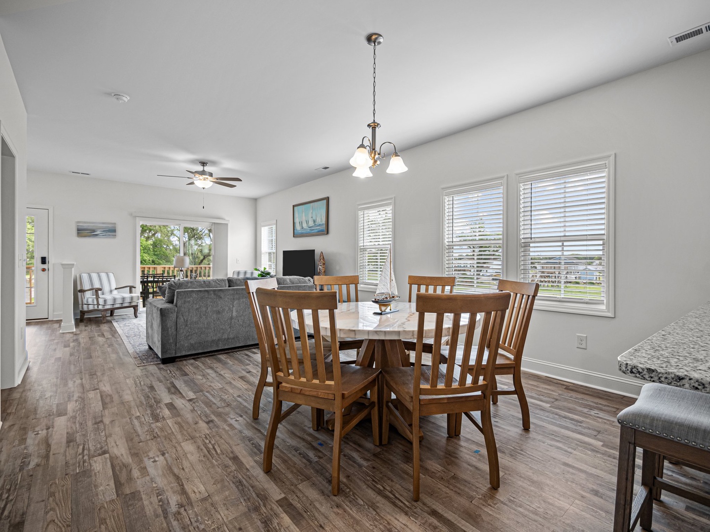 Your bright, open living space flows seamlessly from dining to living room, with gleaming hardwood floors and coastal charm throughout.