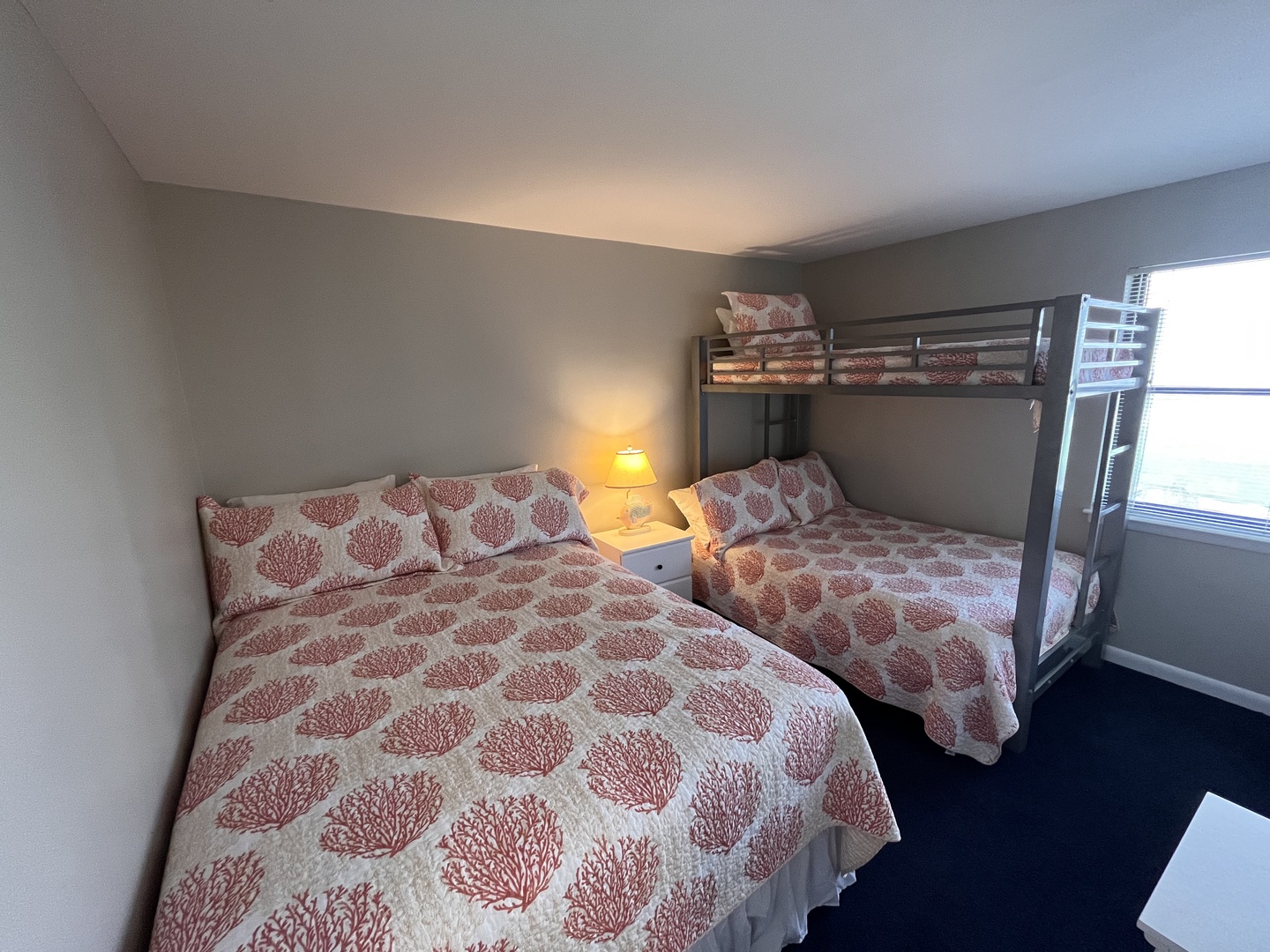 Curl up in your cozy bedroom with charming coral-patterned linens and a bunk bed perfect for families or groups sharing memories together.