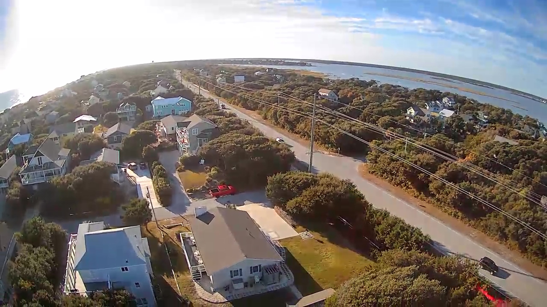 Aerial view of coastal community featuring vacation homes nestled among native vegetation with nearby beach access and waterfront setting.
