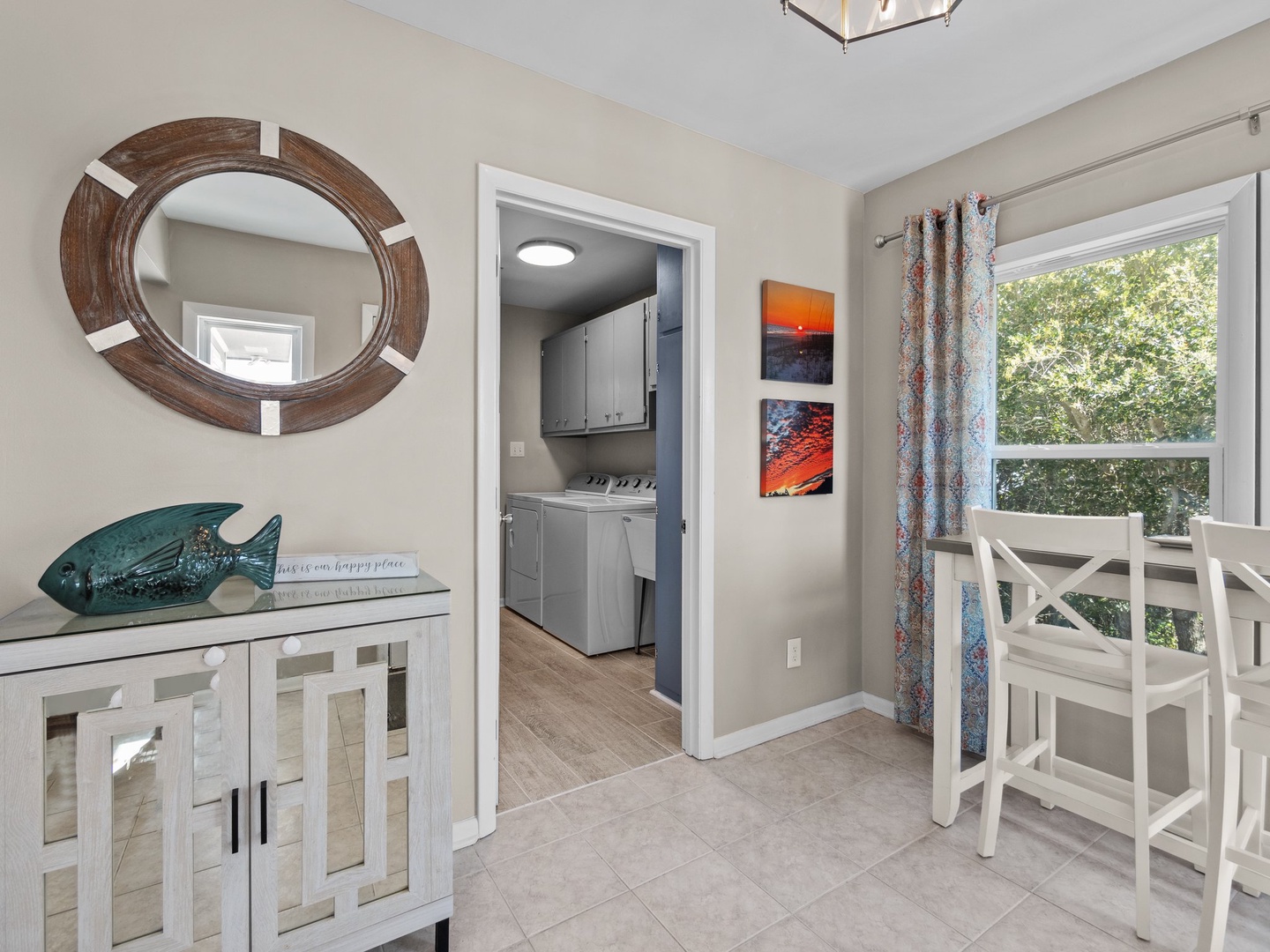 Gather around your bright dining area with white chairs and sideboard, featuring coastal decor and easy kitchen access.